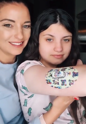 Woman and daughter with dog party dexcom G6 tape and transmitter sticker on arm