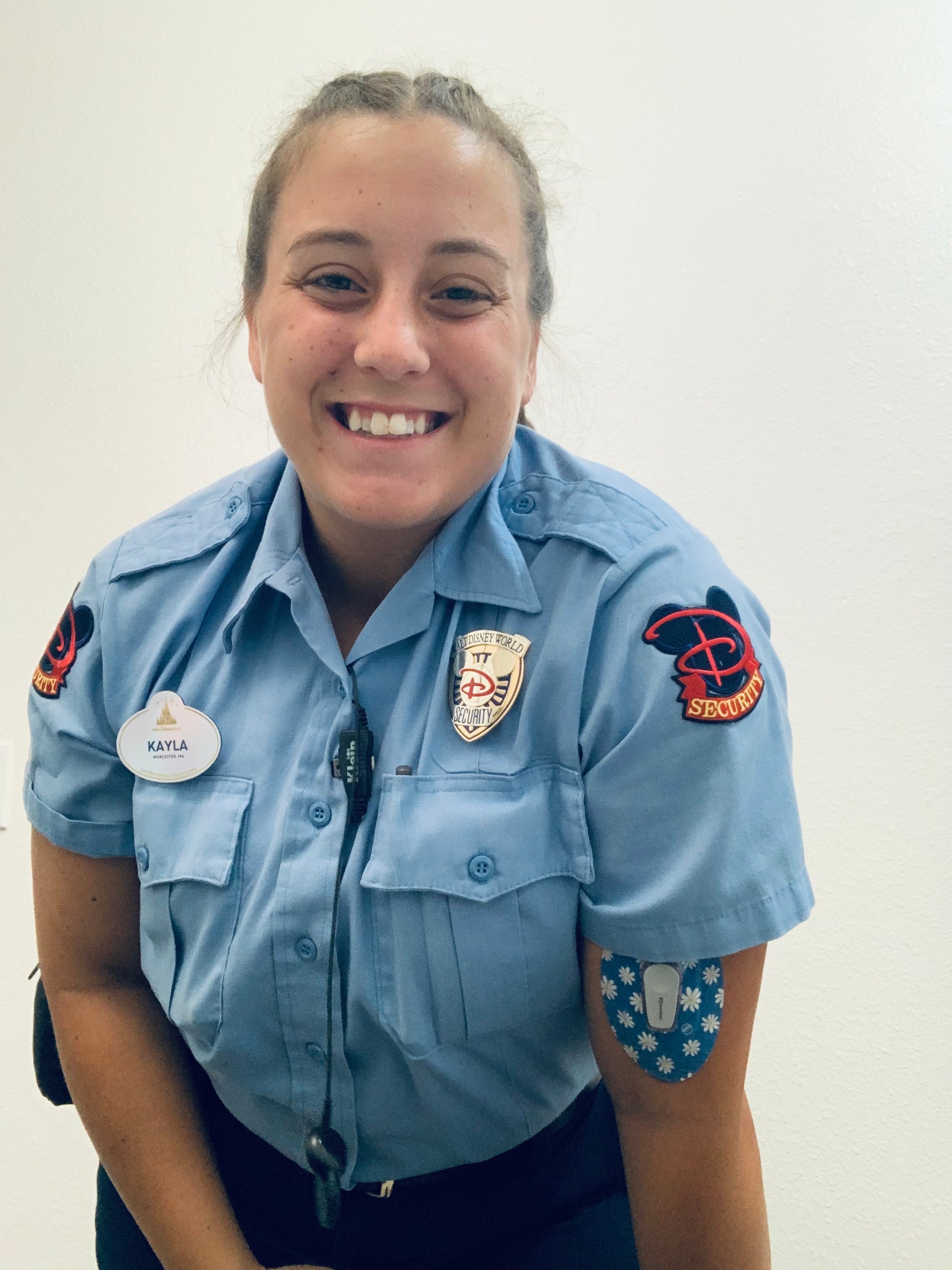 ExpressionMed Woman in Disney Security uniform with Painted Daisies Dexcom G6 Tape on arm