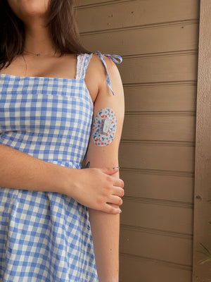 ExpressionMed Girl in blue checker dress with Patriotic Popsicles Dexcom G6 Tape on upper arm