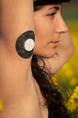 Person in flower feild wearing Freestyle Libre CGM with Expressionmed black marble adhesive tape design